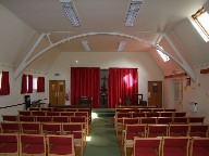 The interior, with its red flush curtains and red modern seating, is reminiscent of a small cinema.